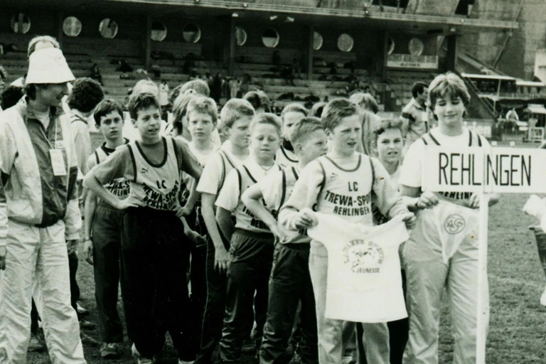 Anke Moos (hinter dem Rehlingen-Schild mit dem Wimpel des CASG Paris) als Mannschaftsführerin 1989 bei einem Vergleichskampf in Paris neben dem Prinzenpark- Stadion
